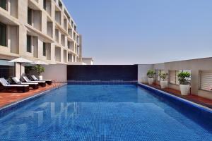 Four Points by Sheraton Jaipur, City Square في جايبور: مسبح في فندق فيه كراسي ومبنى