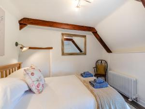 1 dormitorio con cama, espejo y silla en The Bing en Buckland in the Moor