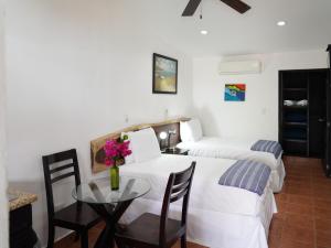 um quarto de hotel com duas camas e uma mesa com flores em Room to Roam em Rivas