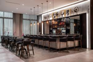 un bar en un restaurante con mesas y sillas negras en The Row Hotel at Assembly Row, Autograph Collection, en Somerville