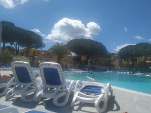 duas cadeiras sentadas em frente a uma piscina em Résidence Odalys Saint Loup Appartement Climatisé entierement rénové em Cap d'Agde