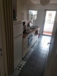 a kitchen with white appliances and a tile floor at appartement terrasse pkg au pied plages du prado in Marseille