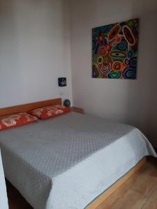 een slaapkamer met een bed met een schilderij aan de muur bij Casa DALU a Roma nel cuore di Ostia Antica in Ostia Antica