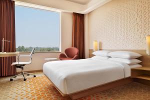 a bedroom with a large bed and a desk and a chair at Fairfield by Marriott Chennai Mahindra World City in Chengalpattu