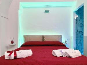 1 dormitorio con 1 cama roja y 2 toallas en Messapica Home, en Ceglie Messapica