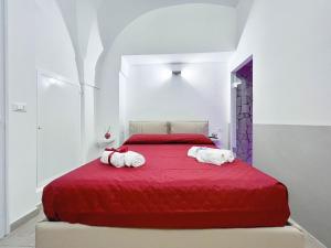 Messapica Home في سيغلي ميسابيكا: غرفة نوم بسرير احمر عليه مناشف