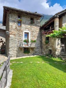 a stone house with flowers in a yard at Bed & Breakfast La Crotta in Pont-Saint-Martin