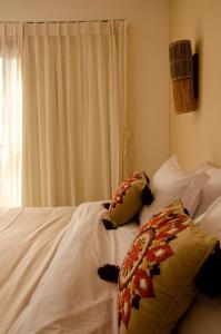 uma cama branca com duas almofadas e uma janela em Casa Makaira em Fernando de Noronha