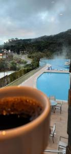 una taza de café frente a la piscina en Golden Gramado Resort en Gramado