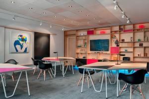 aula con mesas, sillas y TV en Aloft Brussels Schuman, en Bruselas