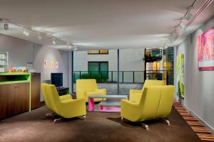 - une salle d'attente avec des chaises jaunes et une table dans l'établissement Aloft Brussels Schuman, à Bruxelles