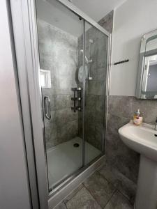 uma casa de banho com um chuveiro e um lavatório. em Petticoat Accommodations em Londres