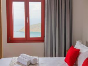 a bedroom with a window and two towels on a bed at Bella Resorts Andros in Andros