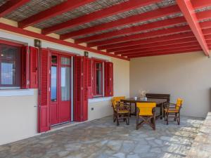 a patio with red doors and a table and chairs at Bella Resorts Andros in Andros