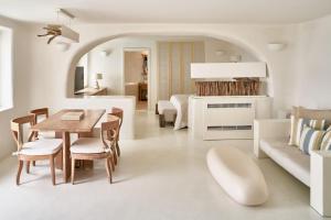 イアにあるミスティーク ア ラグジュアリー コレクション ホテル サントリーニの白いリビングルーム(テーブル、ソファ付)