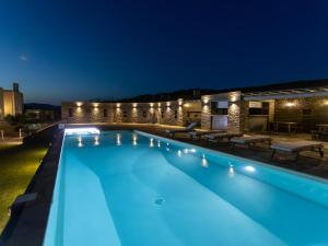 uma piscina iluminada à noite em Bella Resorts Andros em Andros