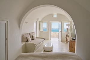 um quarto branco com um sofá e uma mesa em Mystique, a Luxury Collection Hotel, Santorini em Oia
