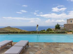 a woman is standing on the edge of a swimming pool at Bella Resorts Andros in Andros