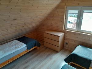 sypialnia z łóżkiem i oknem w drewnianym domku w obiekcie Słoneczna Wyspa Domki w Gdańsku