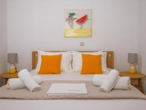 a bed with orange and white pillows and a laptop on it at Bella Resorts Andros in Andros
