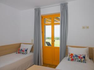 a room with two beds and a orange door at Bella Resorts Andros in Andros