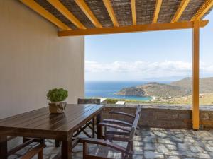 a wooden table and chairs on a patio with a view of the ocean at Bella Resorts Andros in Andros