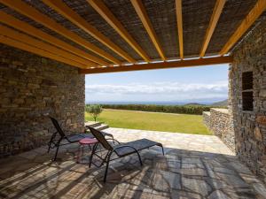 two chairs and a table on a patio with a view at Bella Resorts Andros in Andros