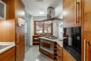 una cocina con electrodomésticos de acero inoxidable y armarios de madera en Charmoso Apartamento Sacavém en Sacavém