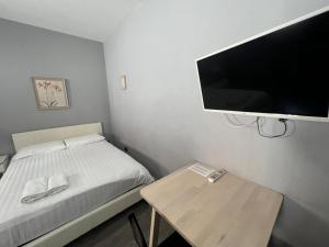 a small bedroom with a bed and a flat screen tv at Petticoat Accommodations in London