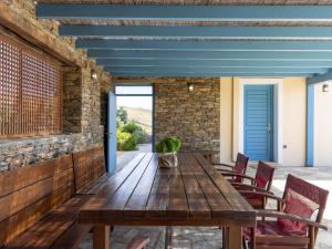 an outdoor patio with a wooden table and chairs at Bella Resorts Andros in Andros