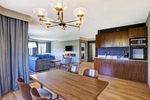 cocina y sala de estar con mesa de madera y sillas en Four Points by Sheraton St. Catharines Niagara Suites, en Thorold