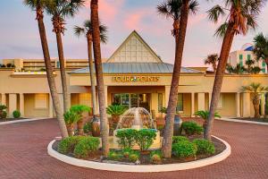 a hotel with palm trees in front of a building at Four Points by Sheraton Destin - Fort Walton Beach in Fort Walton Beach