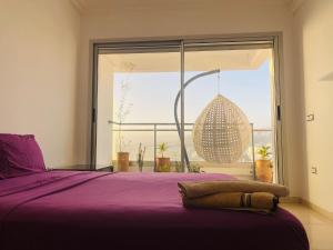 a bedroom with a purple bed and a large window at Beach and Mountain View Surf Apartment in Aourir
