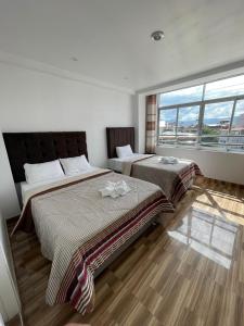 a bedroom with two beds and a large window at HOTEL KILLASUMAQ in Cajamarca