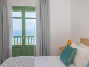 a bedroom with a green door and a window at Bella Resorts Andros in Andros