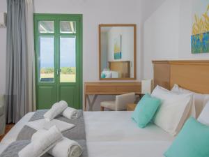 a bedroom with a bed with a green door and a mirror at Bella Resorts Andros in Andros