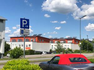 KuppenheimにあるPod-Inn 坡顶公寓-文化谷仓の赤い車は駐車標識の隣に駐車しています。