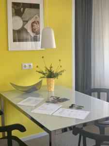 einen Tisch mit einer Blumenvase an einer gelben Wand in der Unterkunft GNAU Rent Jürgen Gnau in Cölbe