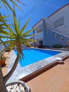a villa with a swimming pool and a palm tree at Casa Madeira in Burgau