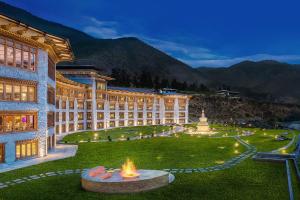 a large building with a fountain in the middle of a lawn at Le Meridien Paro Riverfront in Paro