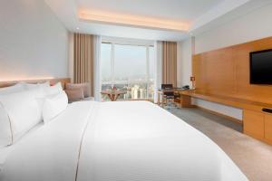 uma grande cama branca num quarto de hotel com televisão em The Westin Mumbai Garden City em Mumbai
