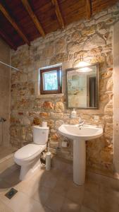 a stone bathroom with a toilet and a sink at Stone Made Private Pool Villas Kriopigi in Kriopigi