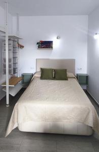 a bedroom with a large white bed with green pillows at Estudio Patio San Paulino in Barbate