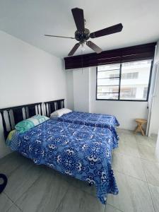 a bedroom with a bed with a blue comforter and a ceiling fan at Departamento hermoso frente a chipipe in Salinas