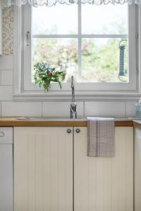 a kitchen sink with a window and a vase of flowers at Scenic Seaside Retreat near Northvolt Ett in Skellefteå