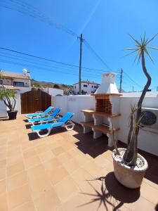 a patio with blue lounge chairs and a table at Casa Madeira in Burgau