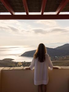 a woman standing on a ledge looking out at the ocean at Bella Resorts Andros in Andros