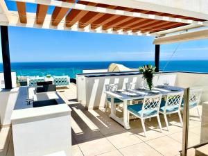 une terrasse avec une table et des chaises et l'océan dans l'établissement Magnificent 3 Bedroom Penthouse, à Fuengirola
