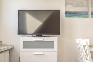 einen Flachbild-TV auf einer weißen Kommode in der Unterkunft Ferienwohnung 'Haus Ingeborg, Wohnung 1/EG' in Cuxhaven