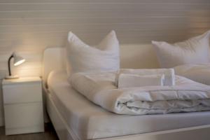 ein Bett mit weißer Bettwäsche und Kissen darauf in der Unterkunft Ferienwohnung 'Haus Ingeborg, Wohnung 1/EG' in Cuxhaven